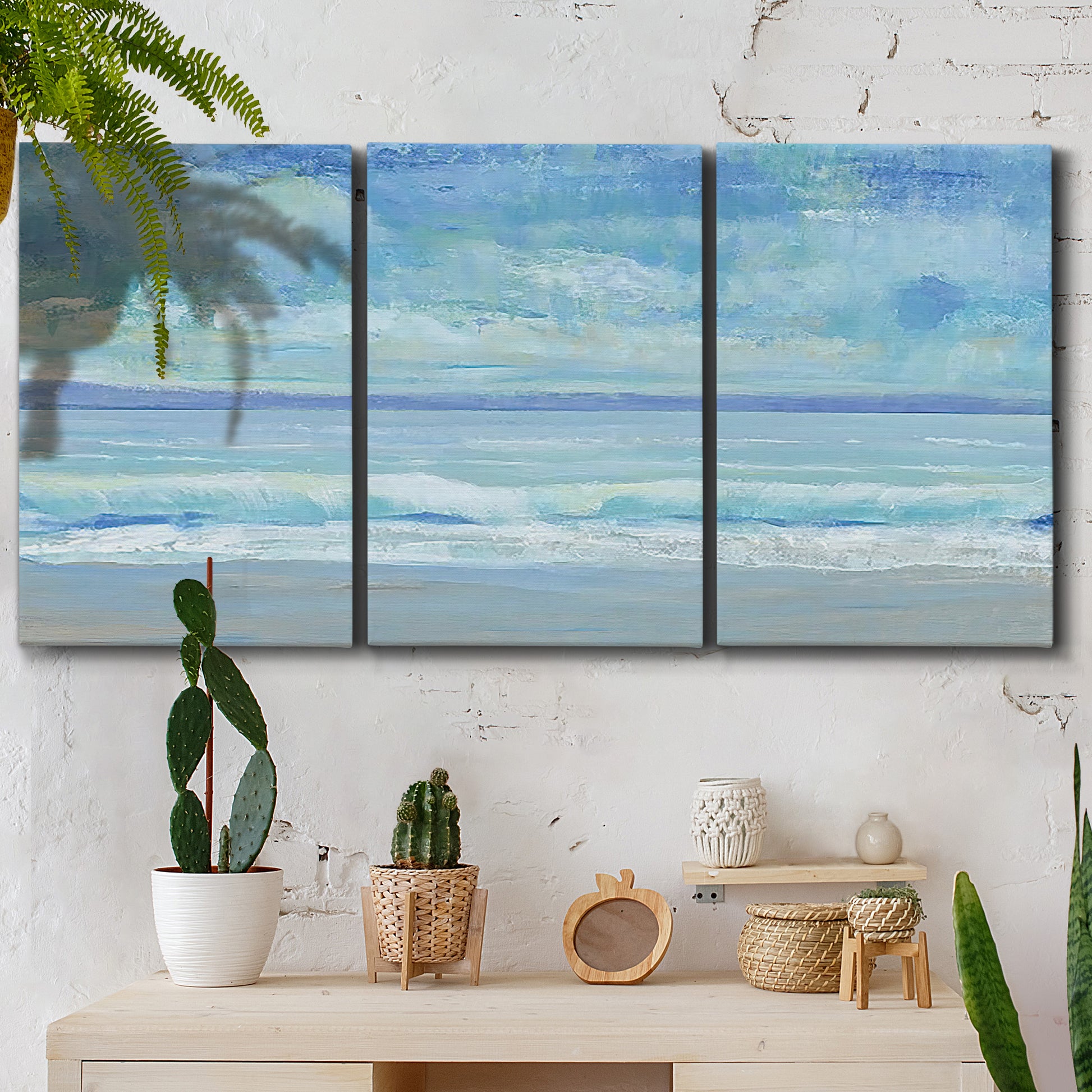 Three-panel canvas wall art featuring rolling ocean surf along shoreline, displayed in a boho-chic entryway above a console table.