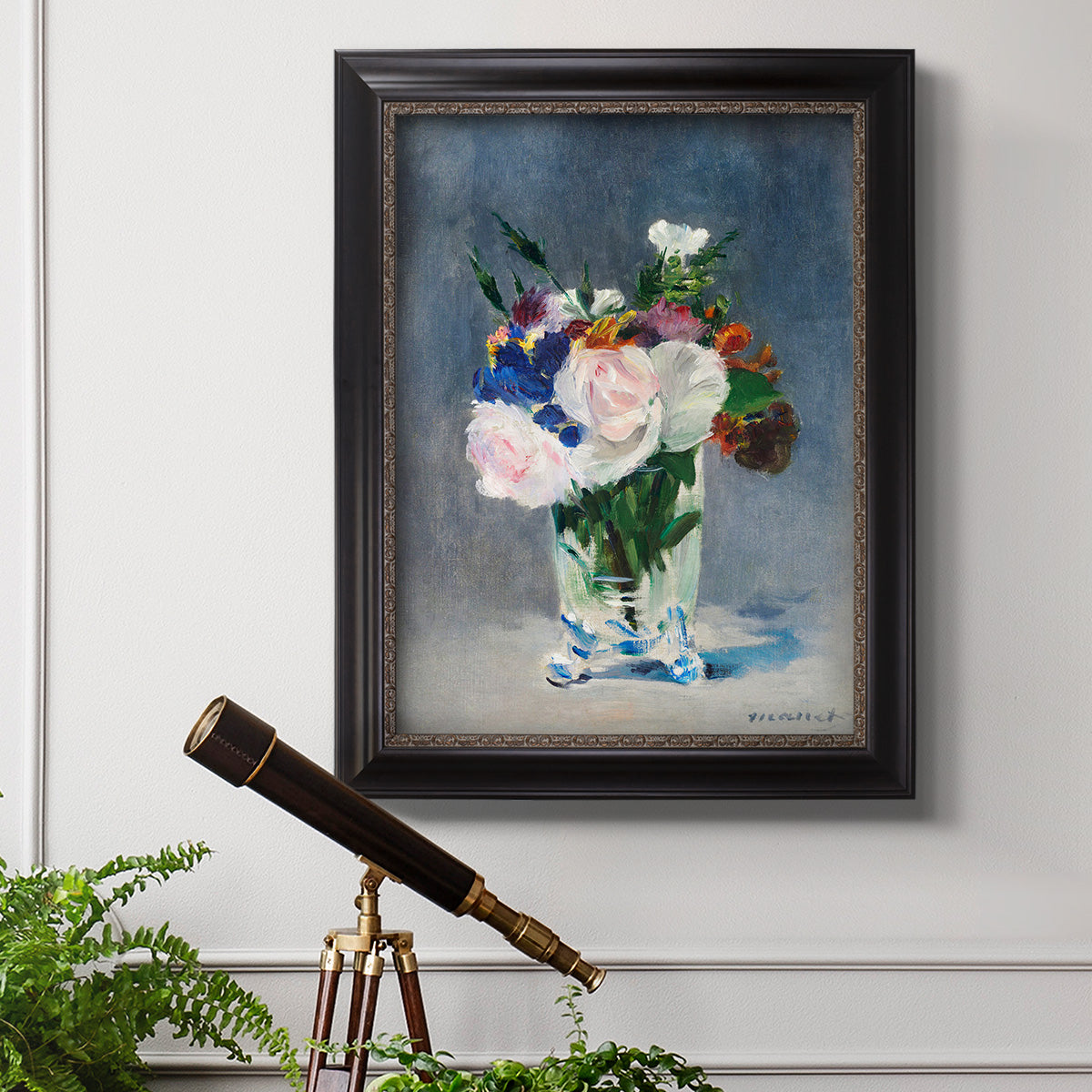 Impressionist floral still life painting by Claude Monet in an ornate black frame with gilded inner detail displayed in a light-toned interior setting.