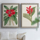 Set of two gray barnwood framed canvas prints depicting large green leaves, red blossoms, and archival cream paper arranged across two complementary compositions above a sofa in a bright living space.