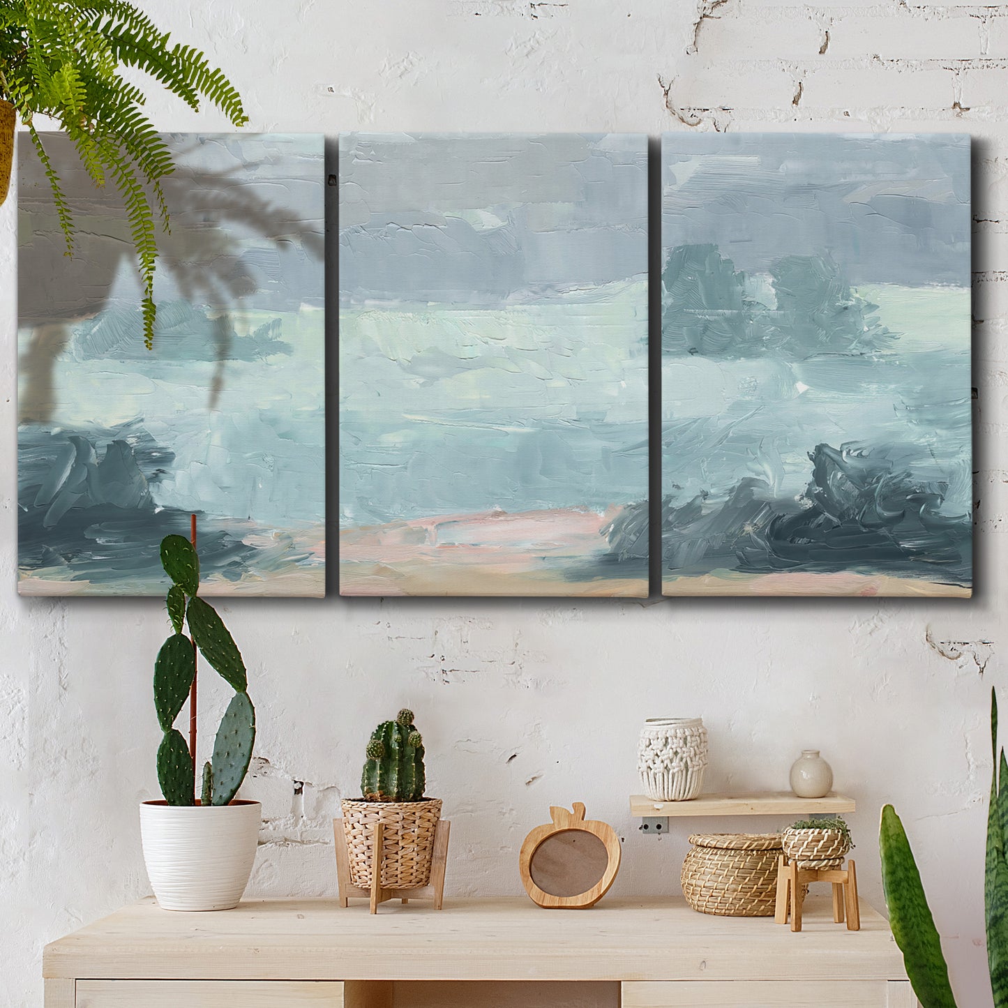 Three-panel canvas wall art featuring soft pastel valley landscape, displayed in a boho-chic entryway above a console table.