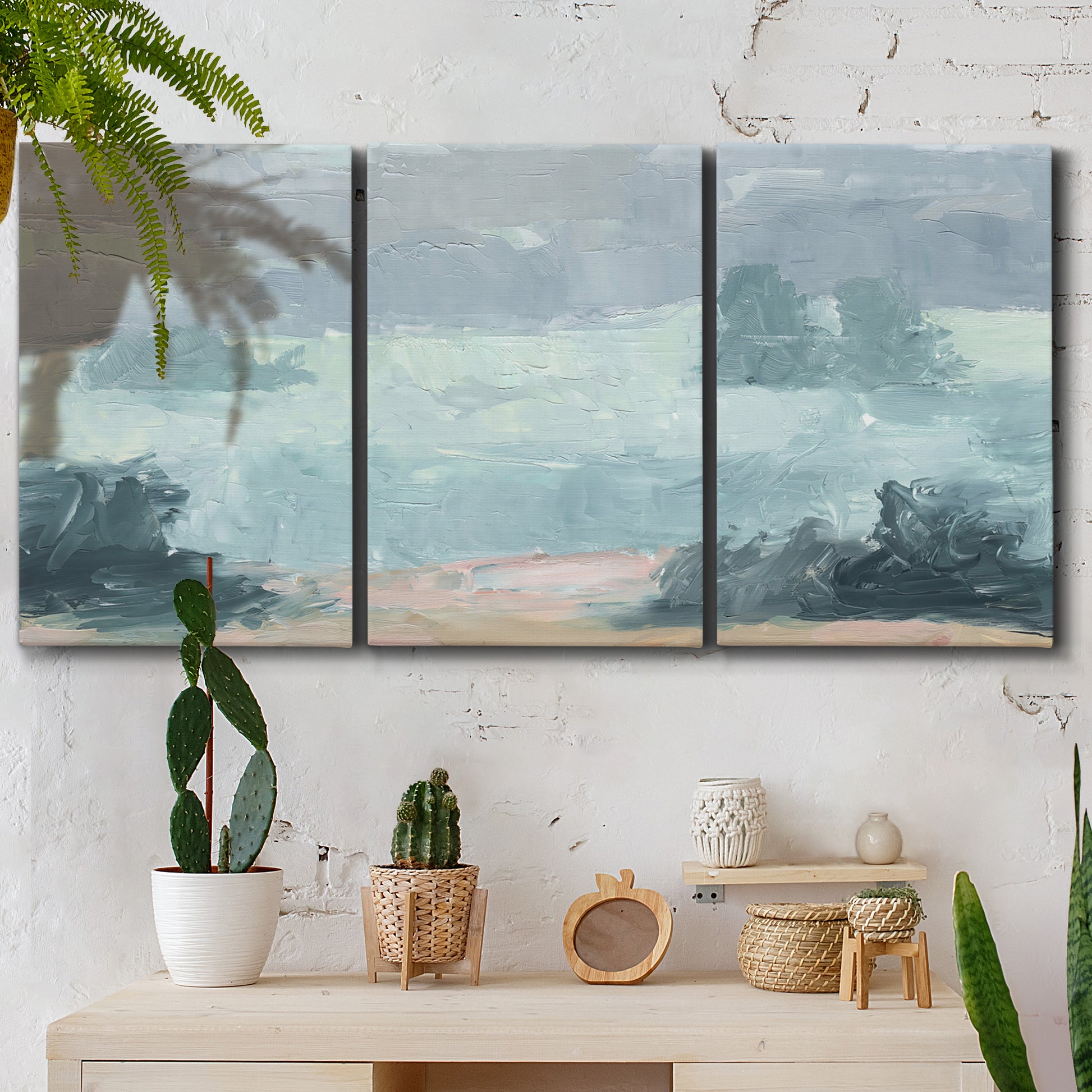 Three-panel canvas wall art featuring soft pastel valley landscape, displayed in a boho-chic entryway above a console table.