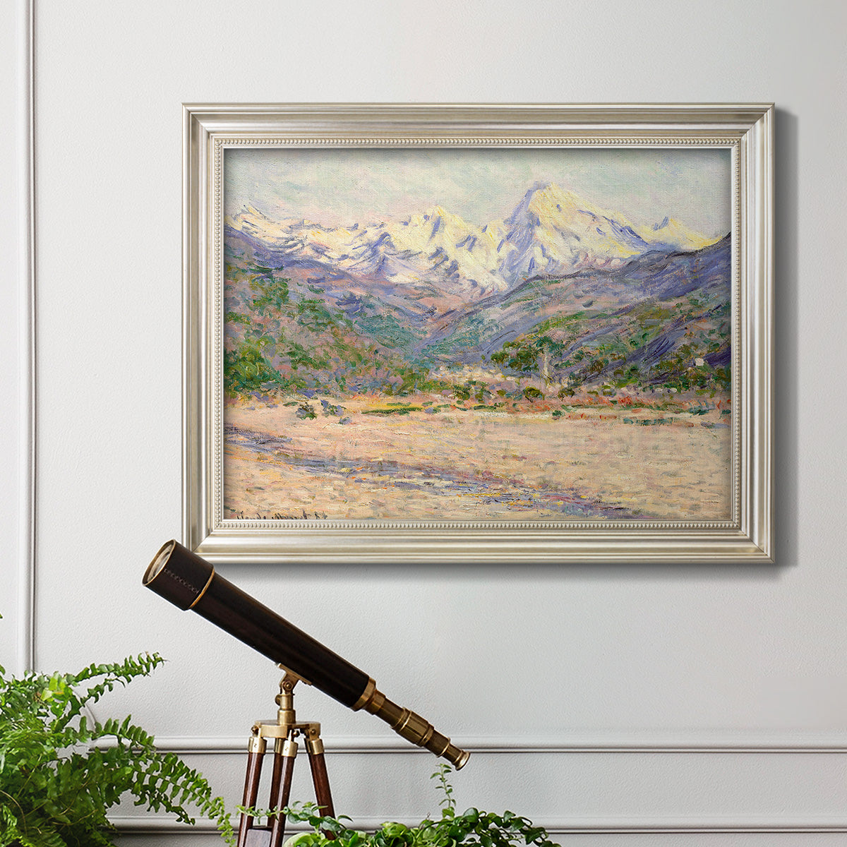 Impressionist valley landscape in southern France by Claude Monet in an ornate champagne frame displayed in a light-toned interior setting.