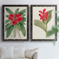 Set of two black barnwood framed canvas prints depicting large green leaves, red blossoms, and archival cream paper arranged across two complementary compositions above a sofa in a bright living space.