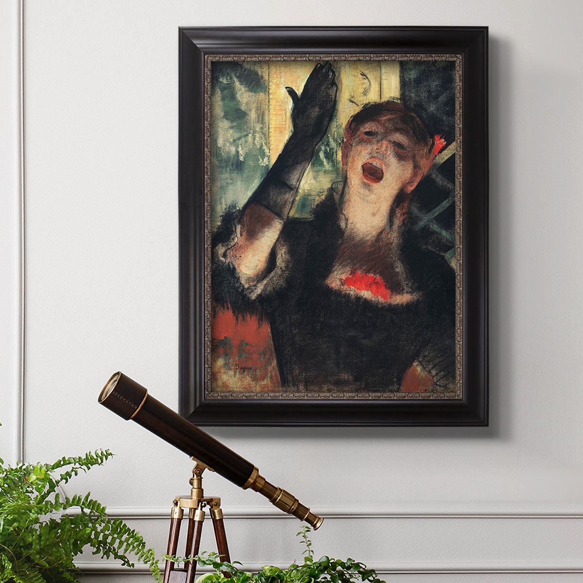 Impressionist portrait of a café singer by Edgar Degas in an ornate black frame with gilded inner detail displayed in a light-toned interior setting.