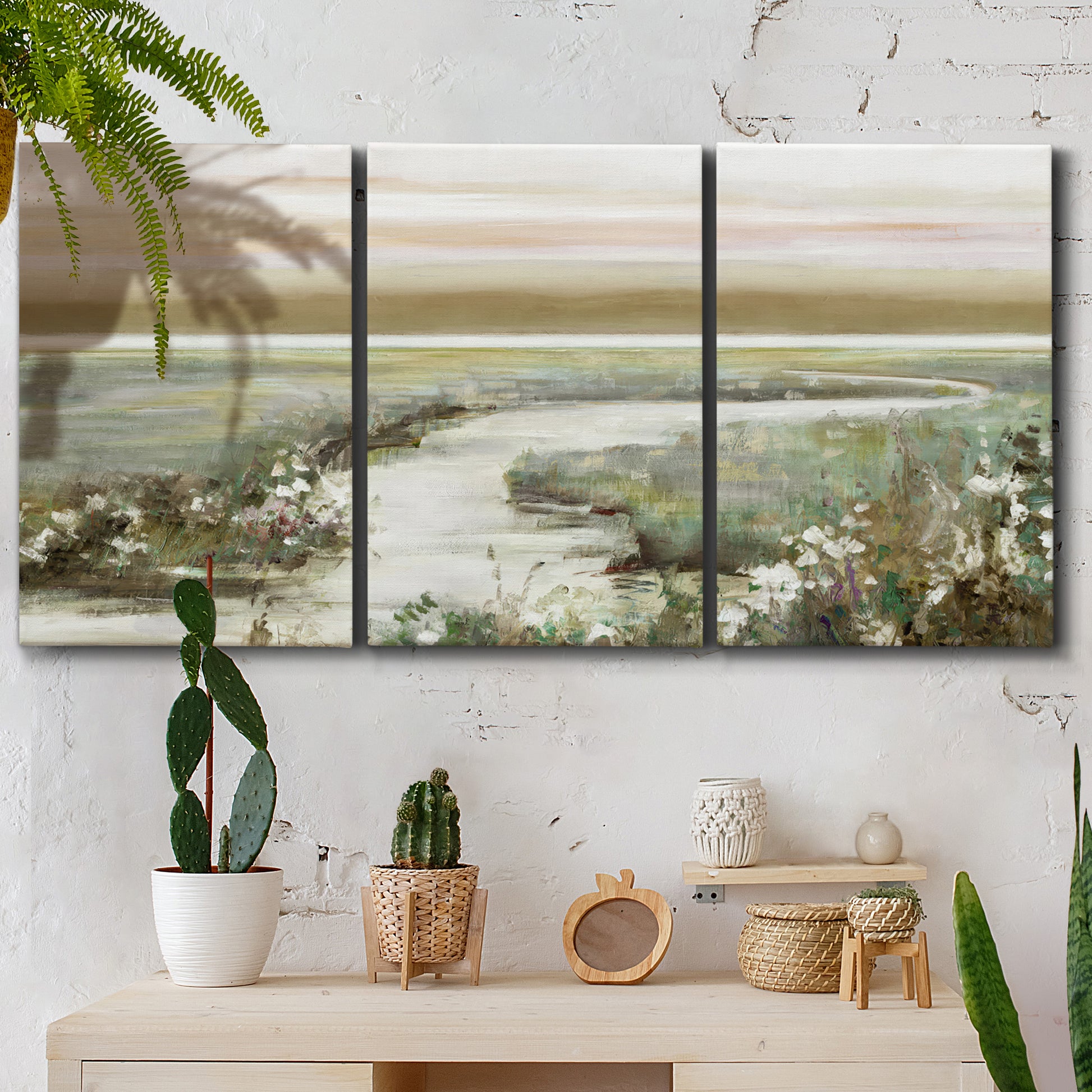 Three-panel canvas wall art featuring pastoral fields under soft sunrise, displayed in a boho-chic entryway above a console table.