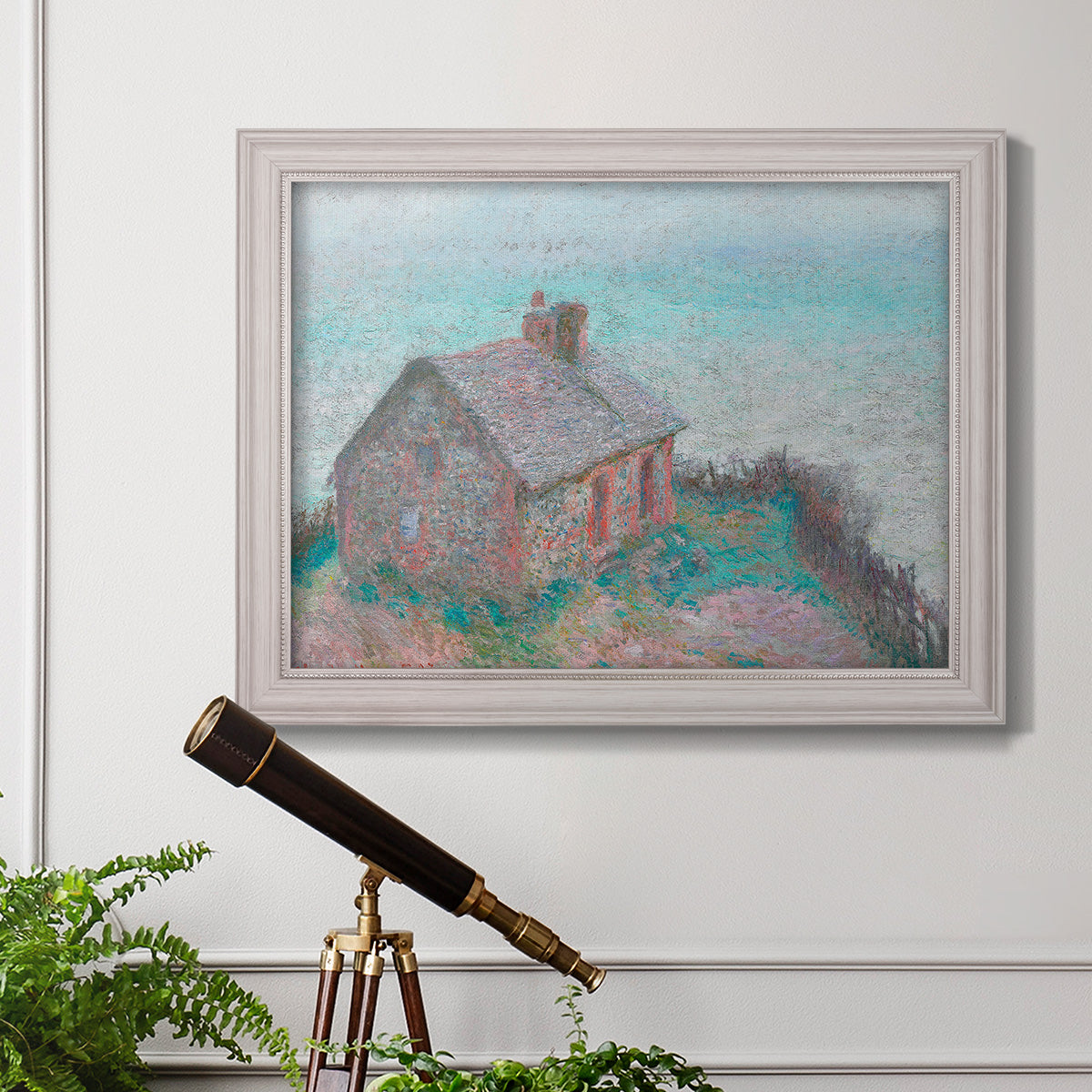 Impressionist coastal building landscape by Claude Monet in an ornate weathered white frame displayed in a light-toned interior setting.