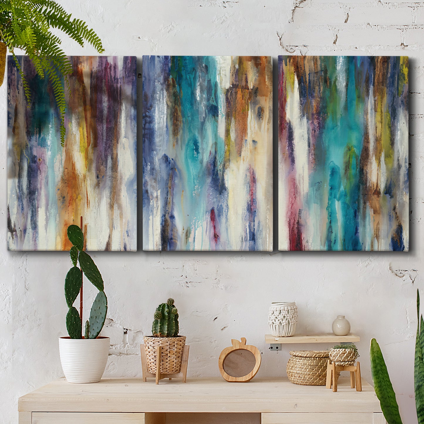 Three-panel canvas wall art featuring abstract shifting color forms, displayed in a boho-chic entryway above a console table.