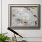 White peonies in bloom in an ornate vintage silver frame displayed in a light-toned interior setting.