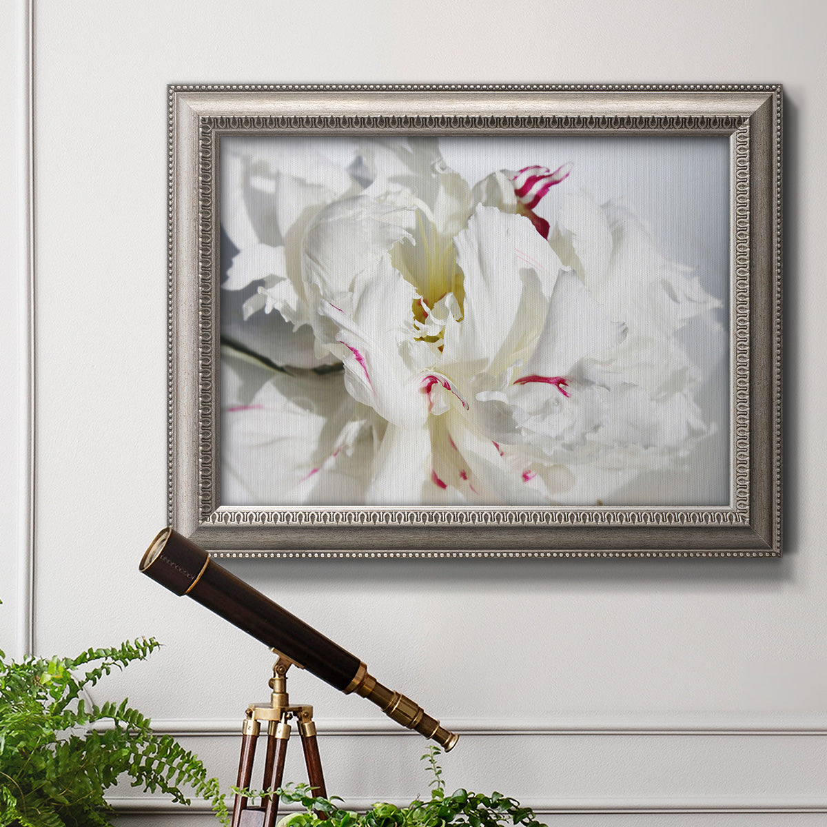 White peony close-up photography in an ornate vintage silver frame displayed in a light-toned interior setting.