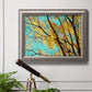 Bright autumn leaves against a blue sky in an ornate vintage silver frame displayed in a light-toned interior setting.