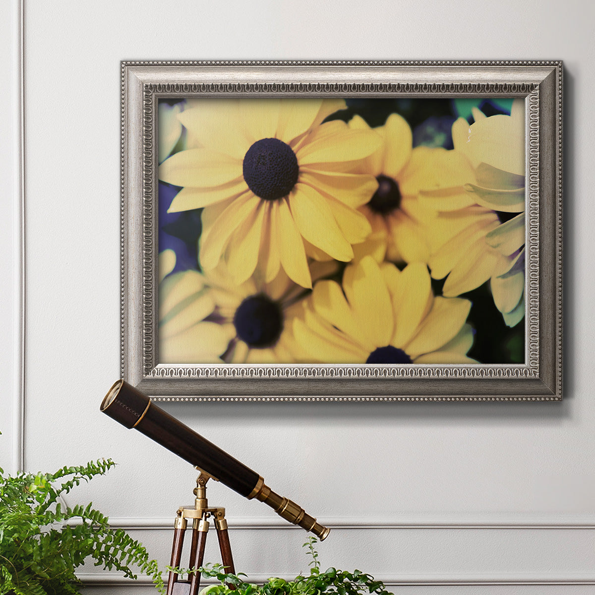 Contemporary black-eyed Susan floral photography in an ornate vintage silver frame displayed in a light-toned interior setting.