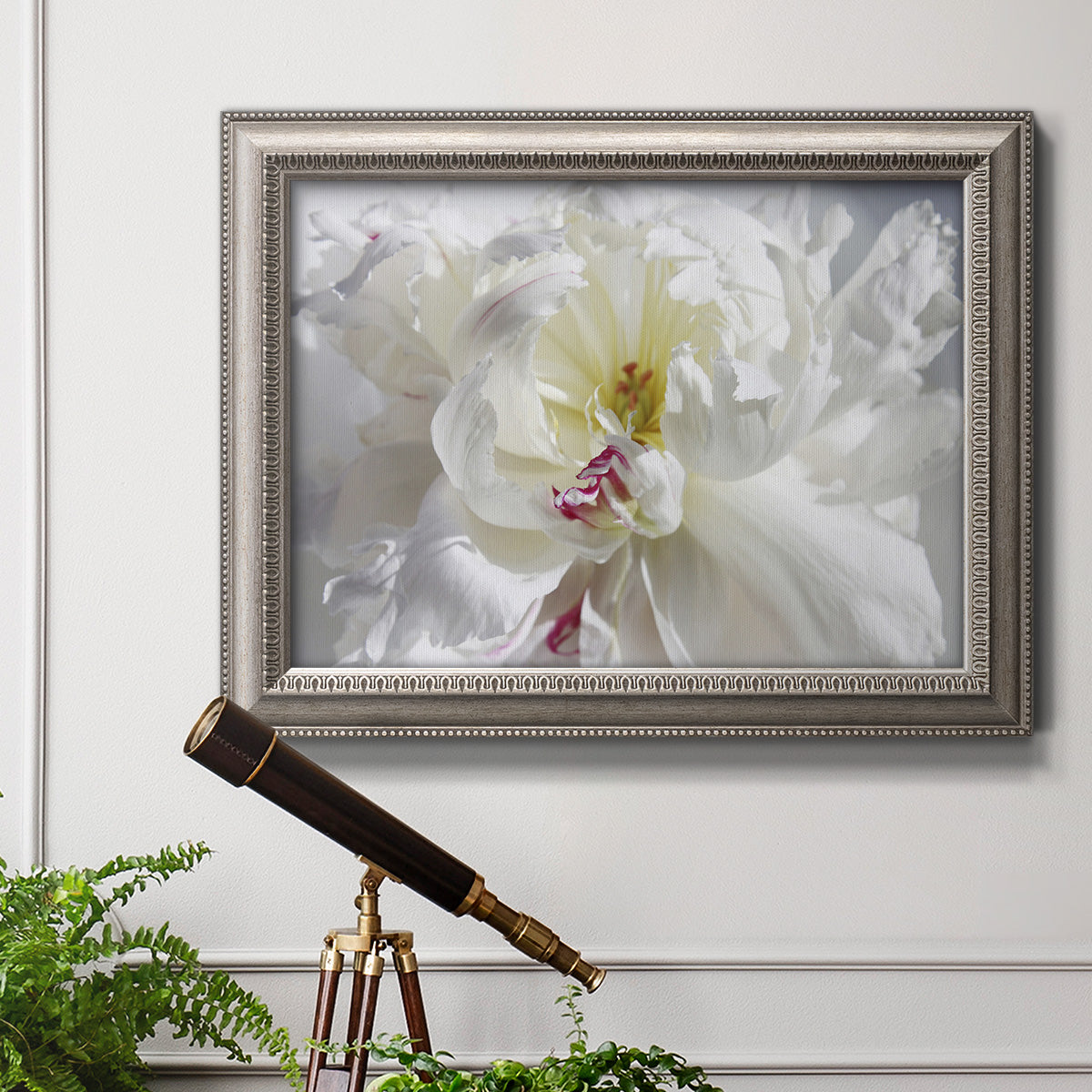 White floral photography close-up in an ornate vintage silver frame displayed in a light-toned interior setting.