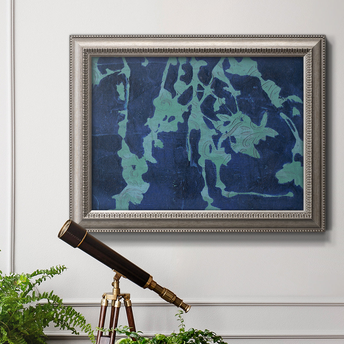Industrial abstract botanical in an ornate vintage silver frame displayed in a light-toned interior setting.