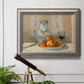 Impressionist still life painting with apples and a ceramic pitcher in an ornate vintage silver frame displayed in a light-toned interior setting.