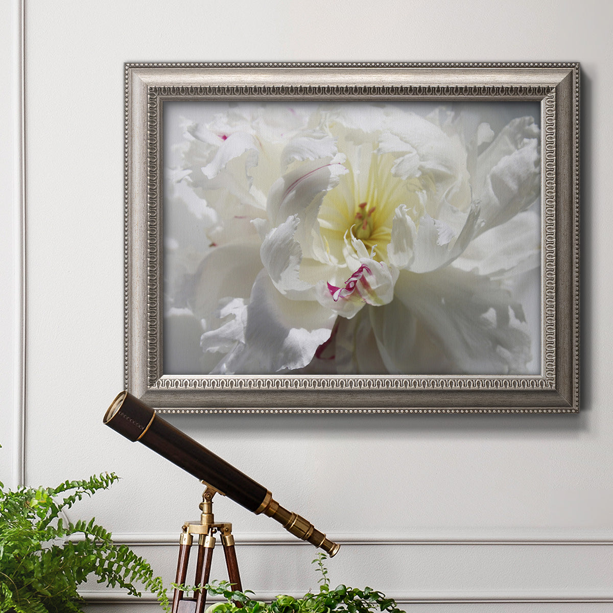 Neutral white peony photography in an ornate vintage silver frame displayed in a light-toned interior setting.