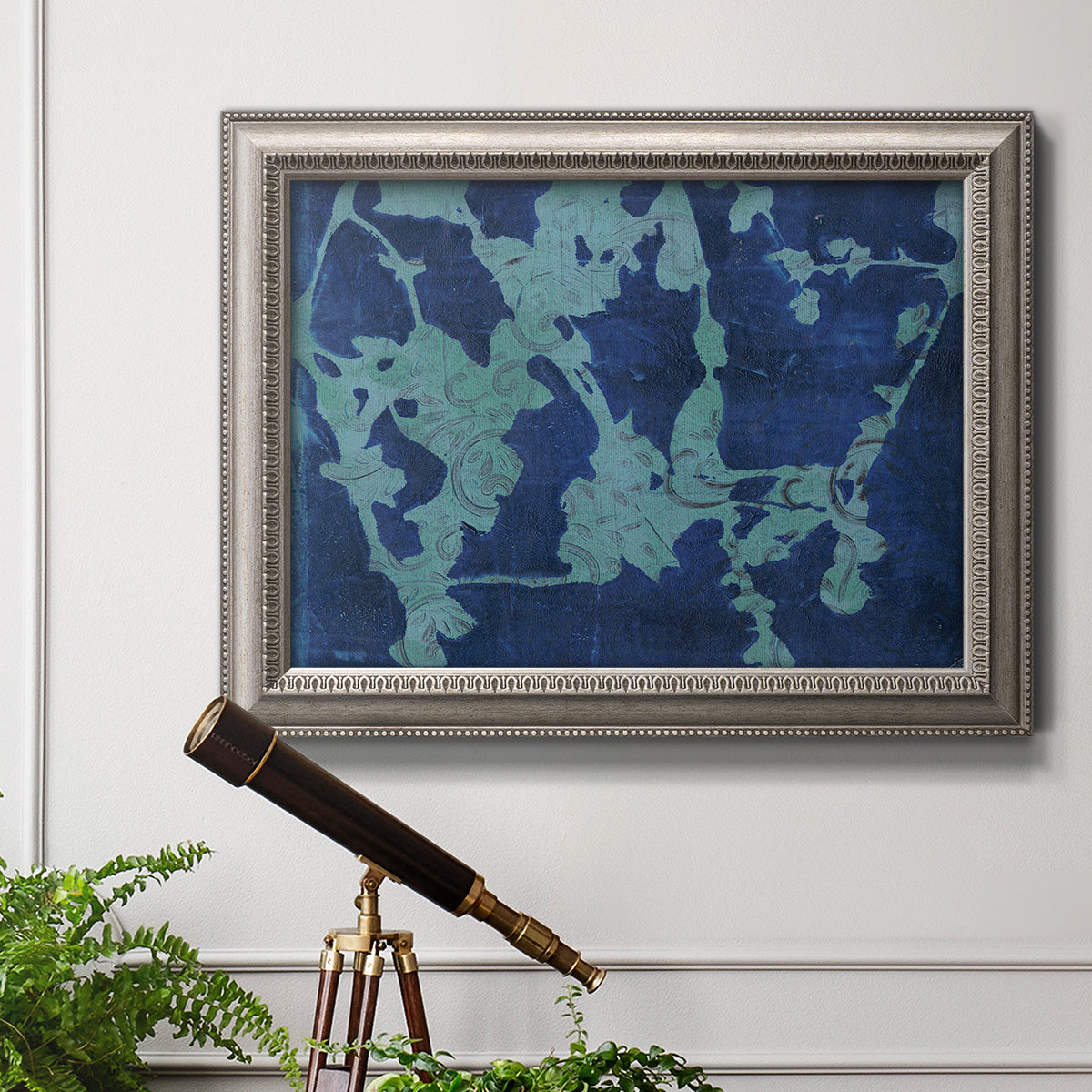 Blue abstract botanical in an ornate vintage silver frame displayed in a light-toned interior setting.