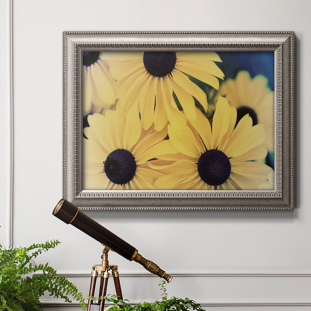 Modern sunflower-style Susan floral photograph in an ornate vintage silver frame displayed in a light-toned interior setting.