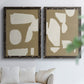 Set of two black barnwood framed canvas prints depicting flat blocky forms, rough painted edges, and strong negative space arranged across two complementary compositions above a sofa in a bright living space.