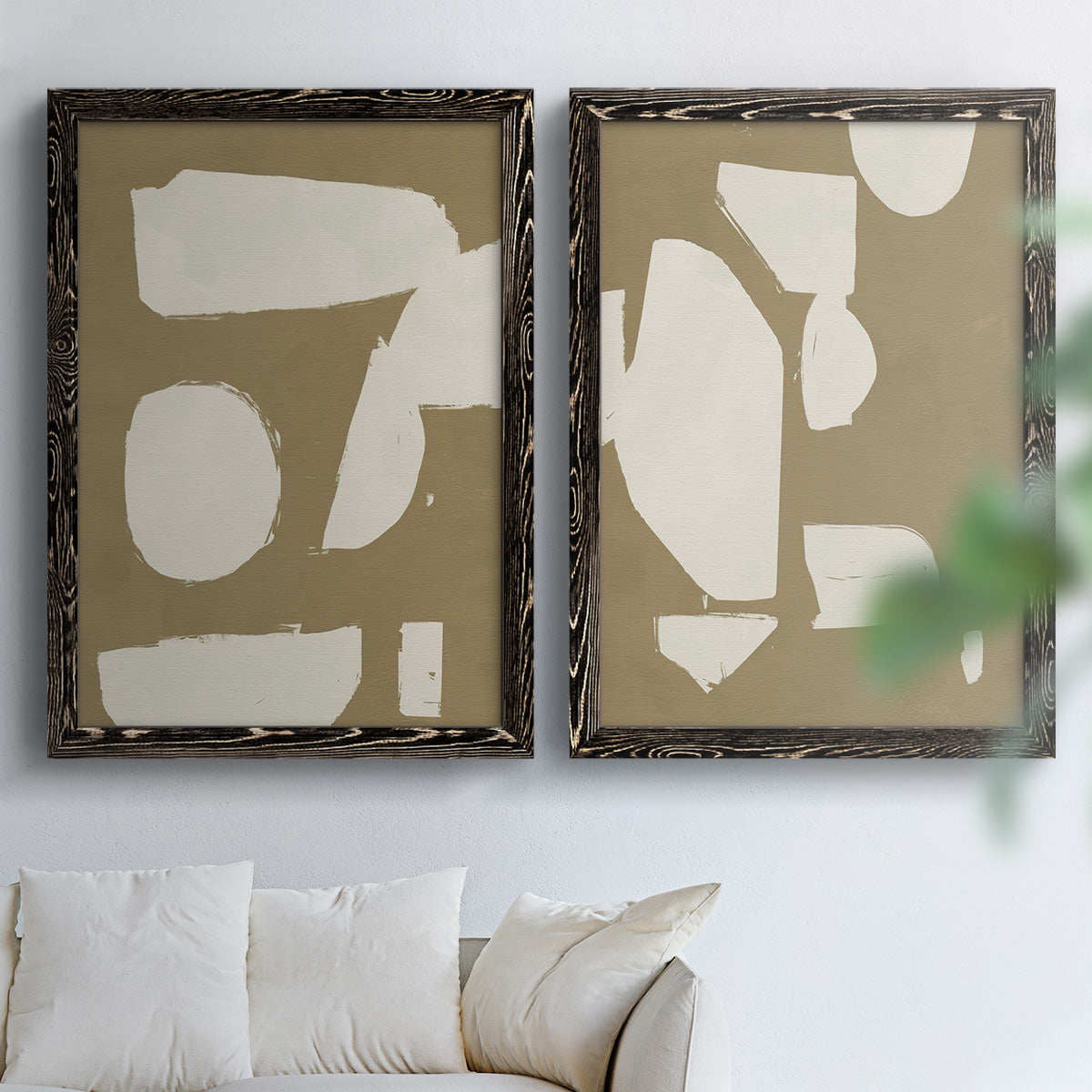 Set of two black barnwood framed canvas prints depicting flat blocky forms, rough painted edges, and strong negative space arranged across two complementary compositions above a sofa in a bright living space.