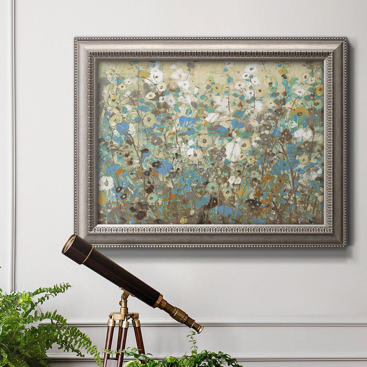 Impressionist flowering vine watercolor artwork in an ornate vintage silver frame displayed in a light-toned interior setting.