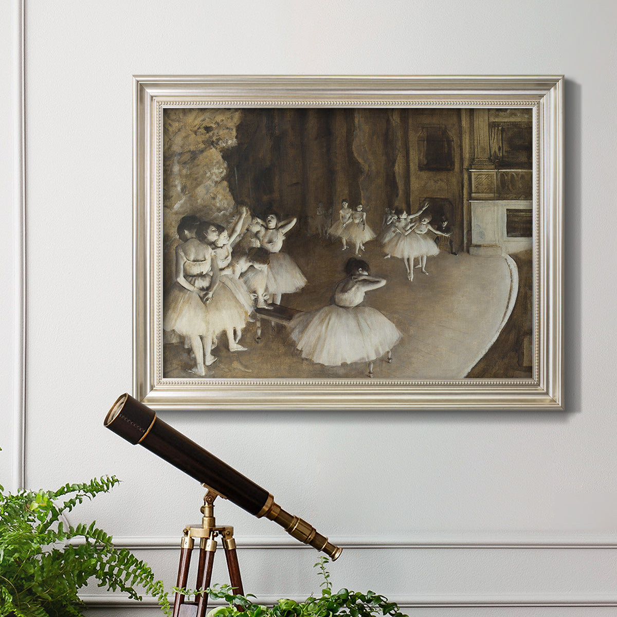 Impressionist ballet rehearsal scene by Edgar Degas in an ornate champagne frame displayed in a light-toned interior setting.