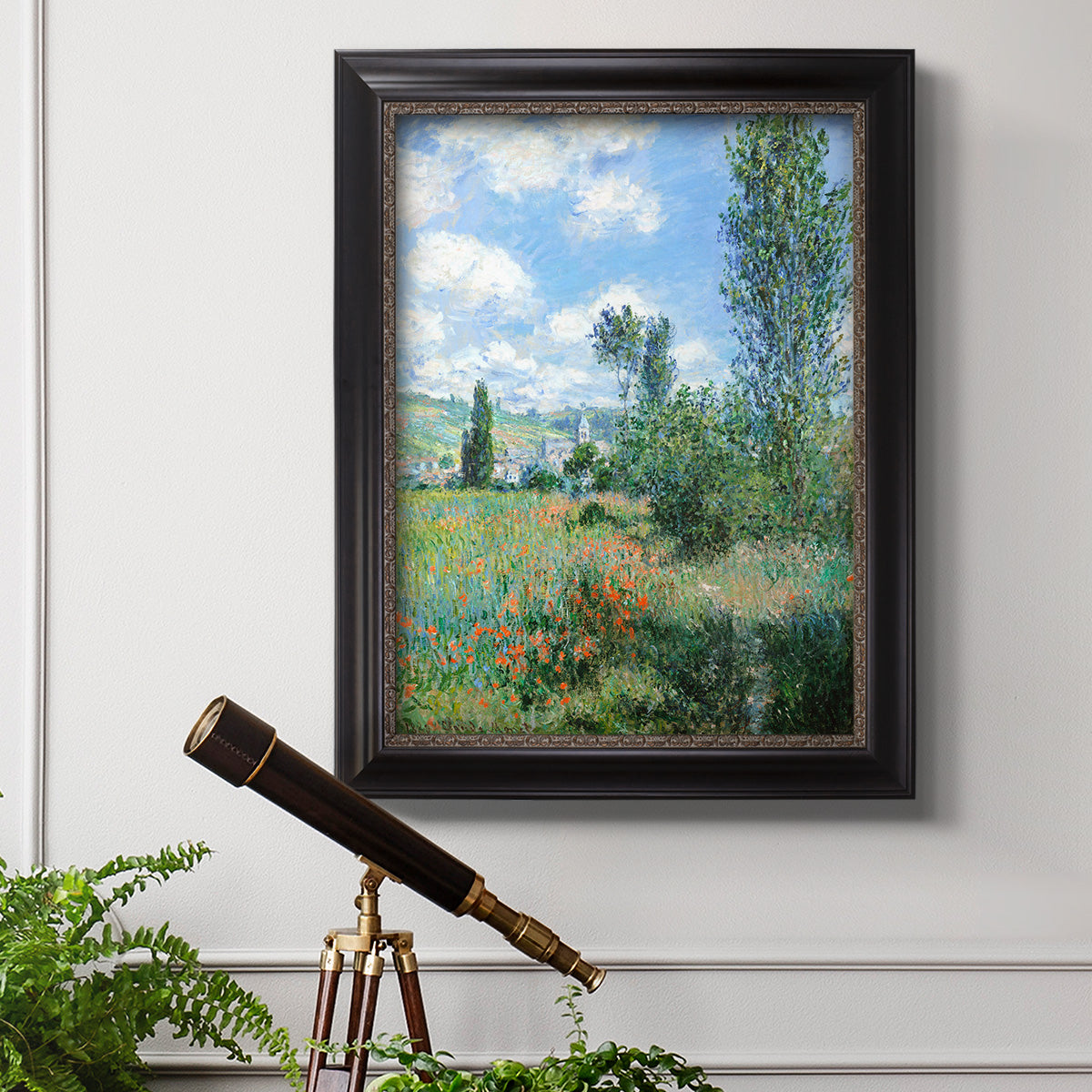 Impressionist pastoral landscape with poppy fields by Claude Monet in an ornate black frame with gilded inner detail displayed in a light-toned interior setting.