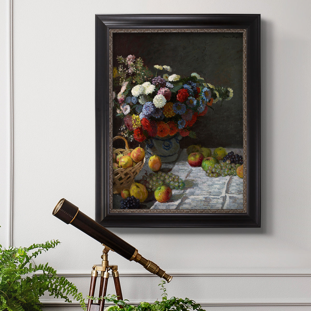 Impressionist floral still life painting by Claude Monet in an ornate black frame with gilded inner detail displayed in a light-toned interior setting.
