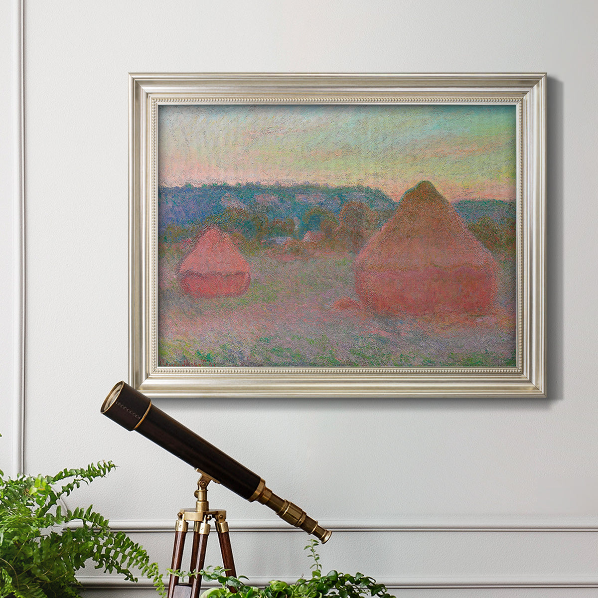 Impressionist haystack series landscape by Claude Monet in an ornate champagne frame displayed in a light-toned interior setting.