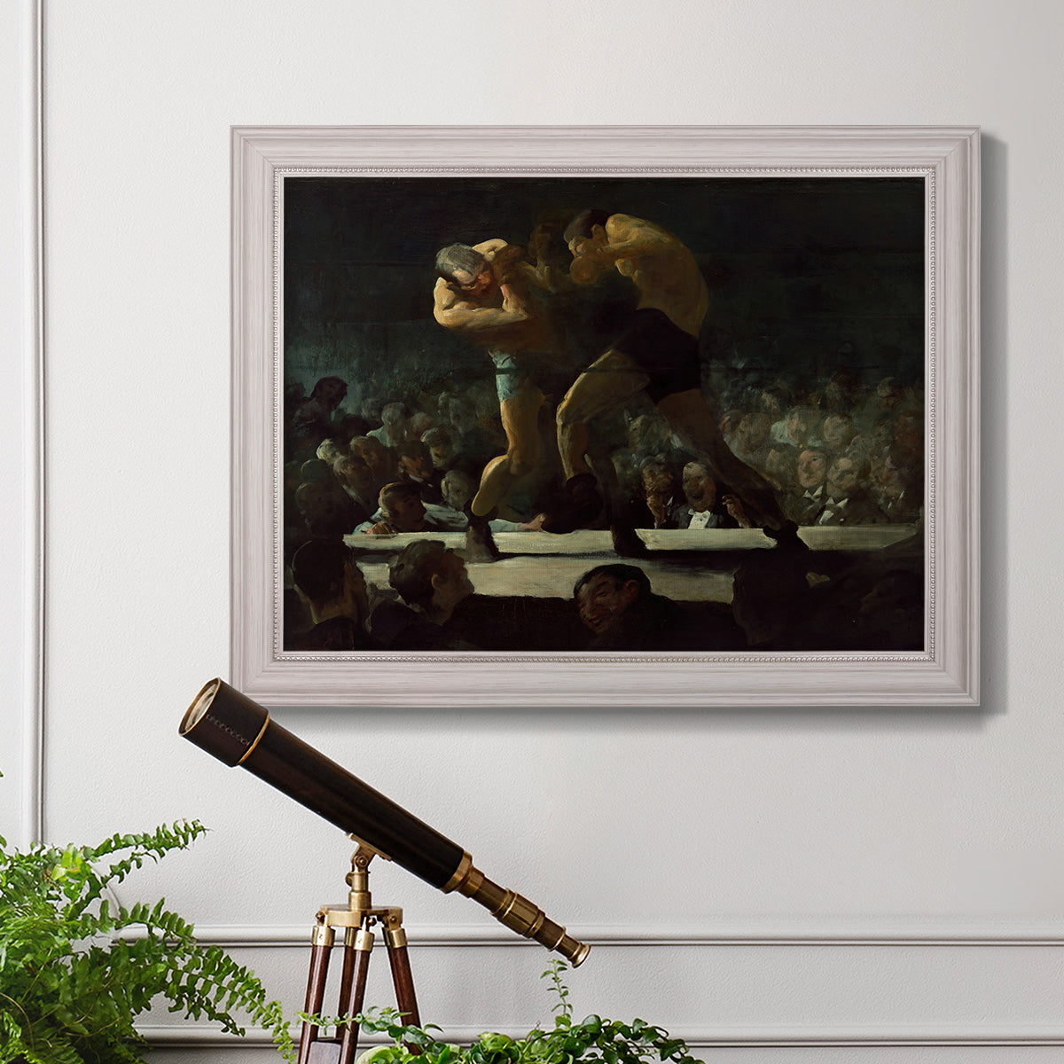 American social club scene painting by George Bellows in an ornate weathered white frame displayed in a light-toned interior setting.