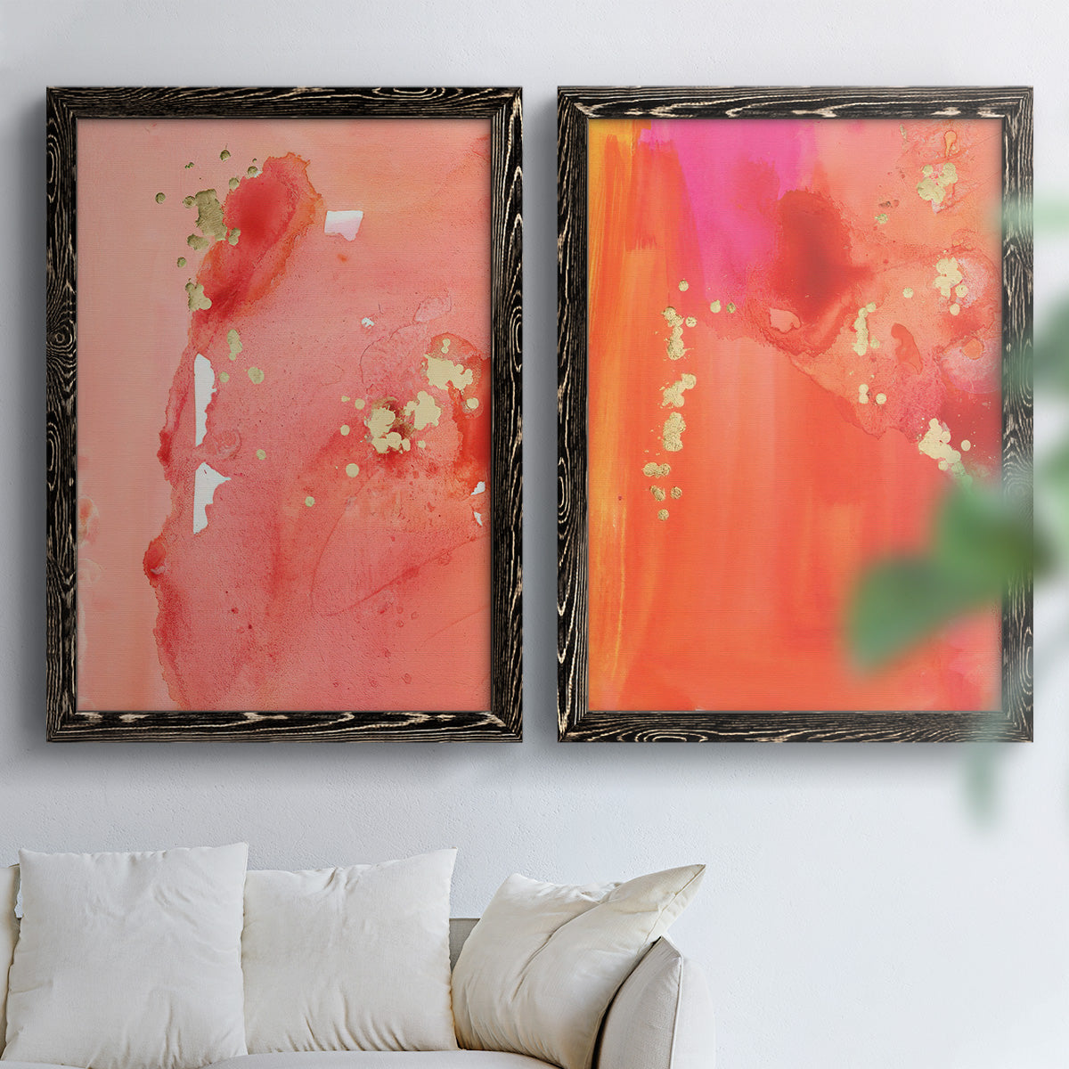 Set of two black barnwood framed canvas prints depicting translucent warm washes, drips, and scattered metallic accents arranged across two complementary compositions above a sofa in a bright living space.