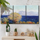 Three-panel canvas wall art featuring mediterranean coastline with headland, displayed in a boho-chic entryway above a console table.
