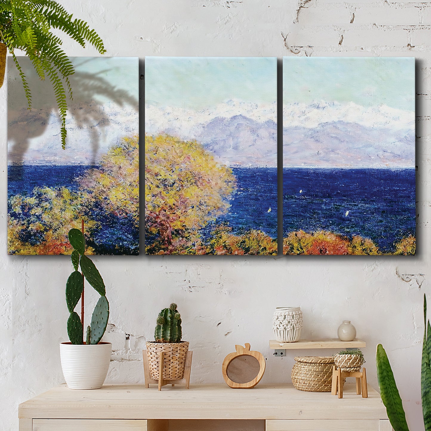 Three-panel canvas wall art featuring mediterranean coastline with headland, displayed in a boho-chic entryway above a console table.