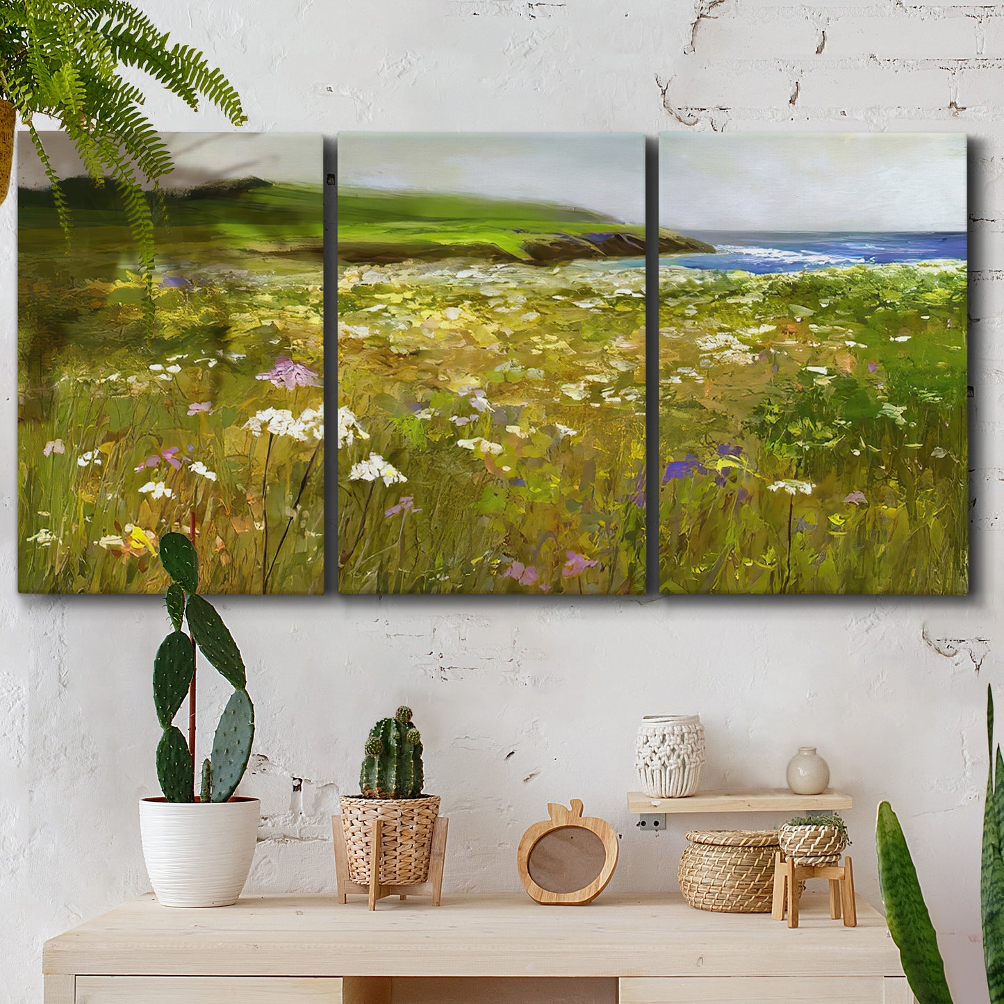 Three-panel canvas wall art featuring rugged coastal cliff landscape, displayed in a boho-chic entryway above a console table.