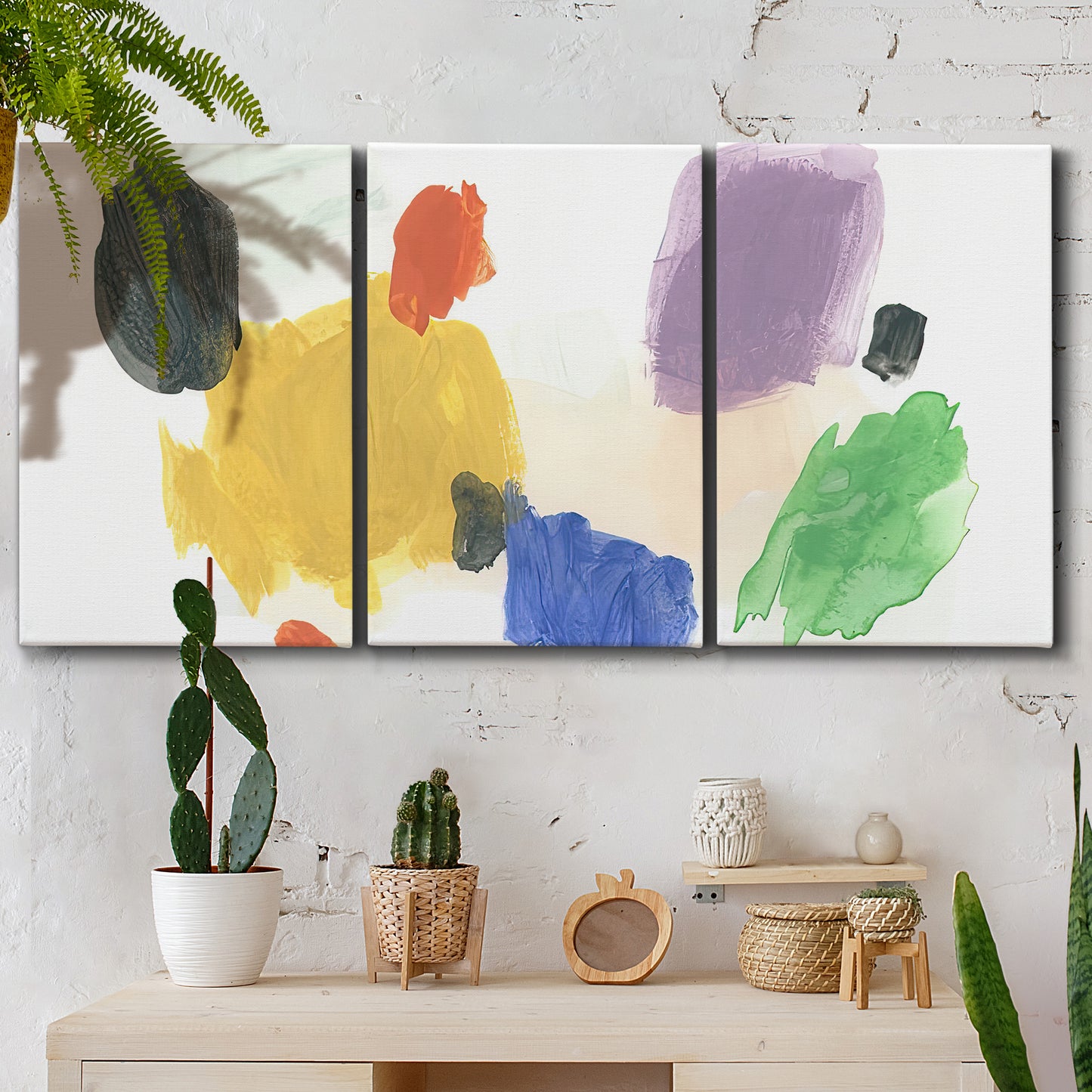 Three-panel canvas wall art featuring inkblot style abstract color symmetry, displayed in a boho-chic entryway above a console table.