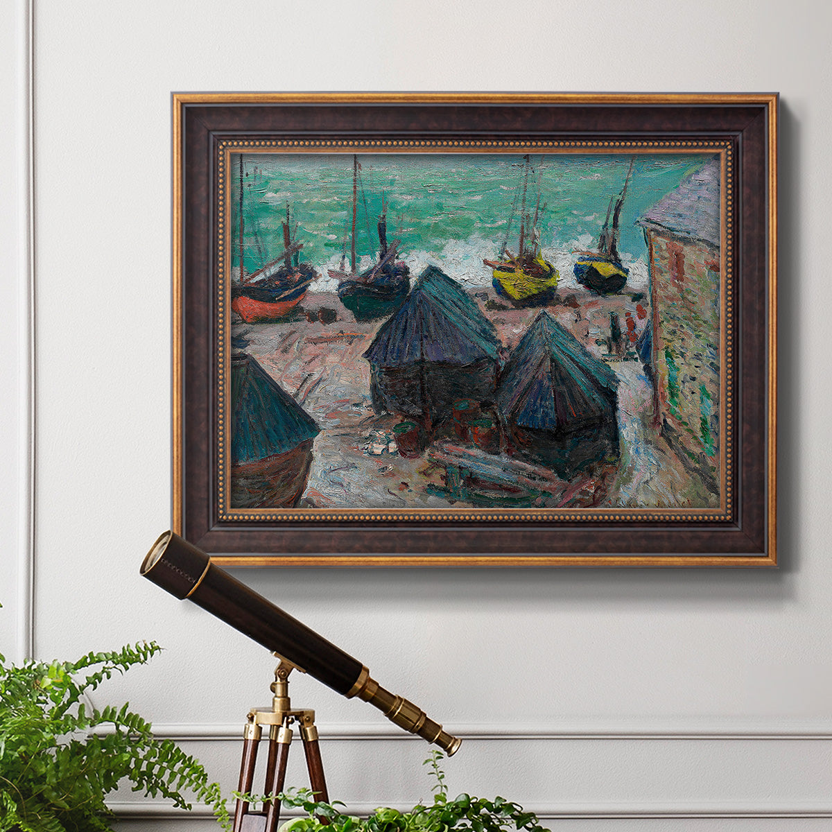 Impressionist coastal beach scene with boats by Claude Monet in an ornate bronzed mahogany wood frame displayed in a light-toned interior setting.