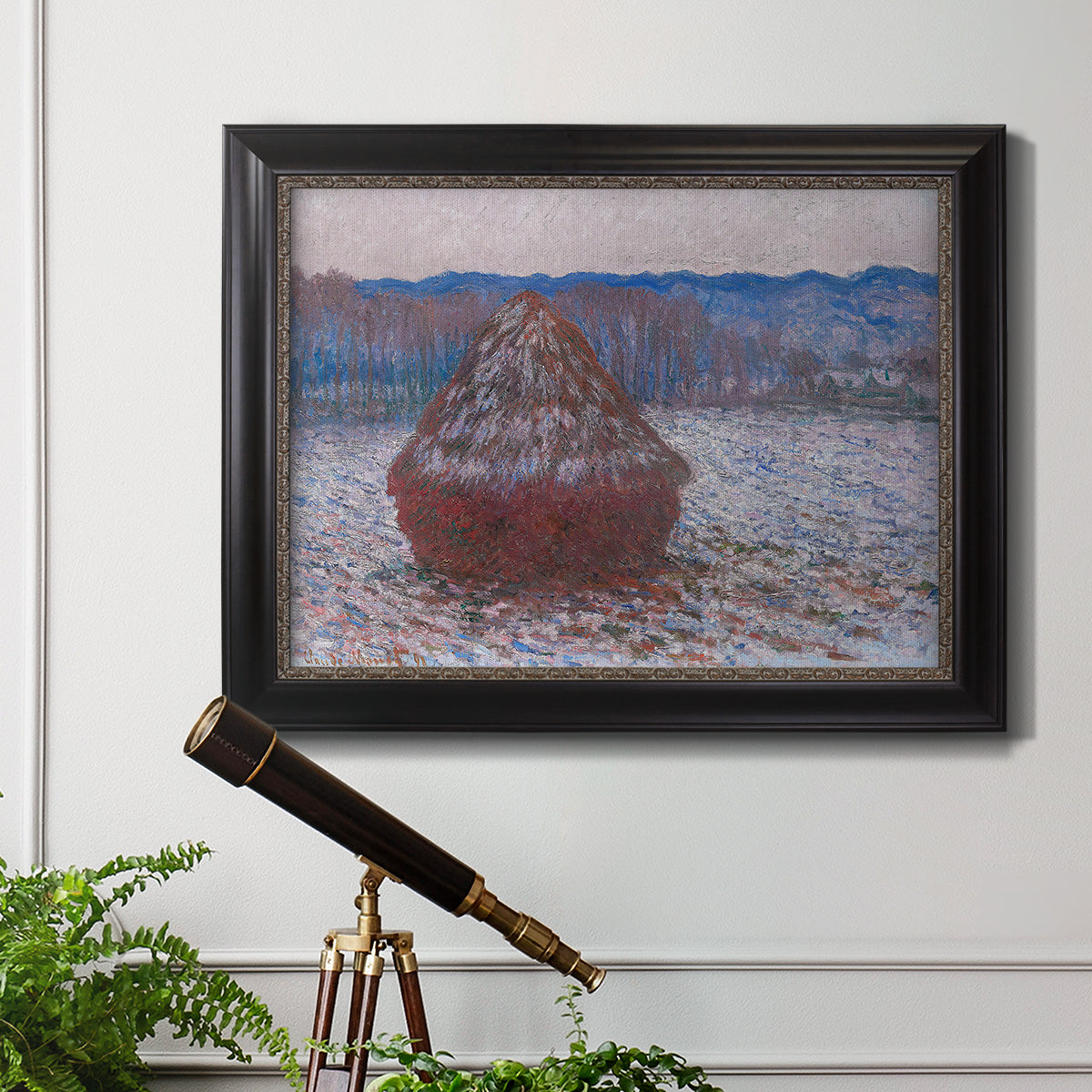 Impressionist single haystack landscape by Claude Monet in an ornate black frame with gilded inner detail displayed in a light-toned interior setting.