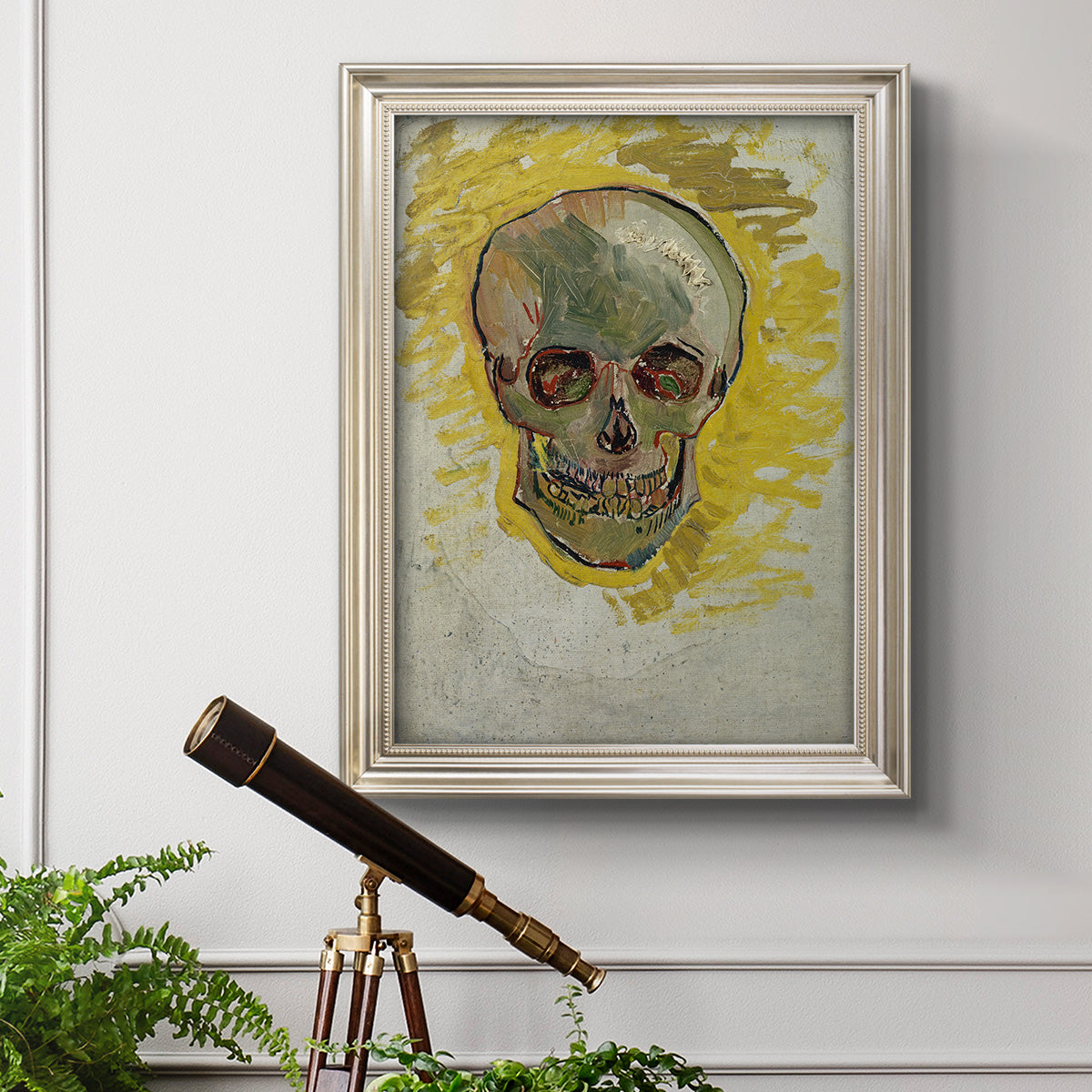 Expressive skull study painting by Vincent van Gogh in an ornate champagne frame displayed in a light-toned interior setting.