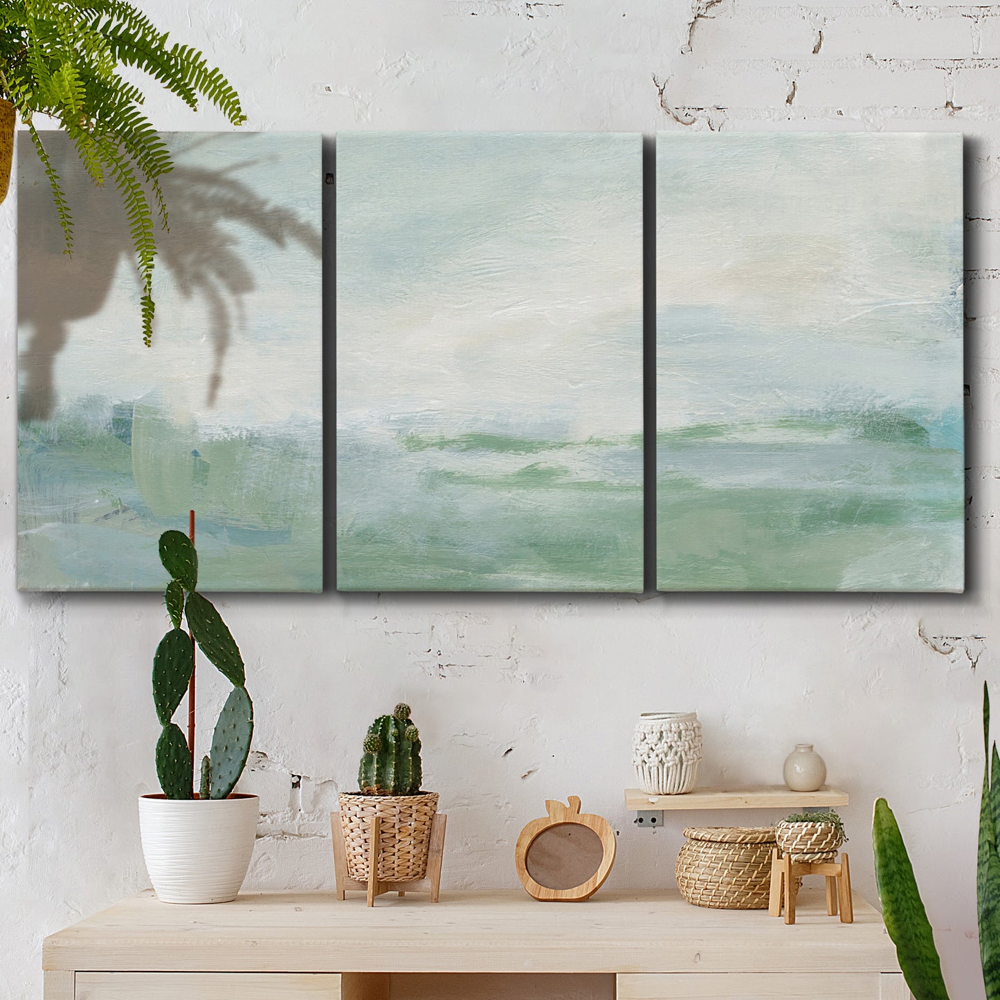 Three-panel canvas wall art featuring soft abstract coastal tones, displayed in a boho-chic entryway above a console table.