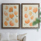 Set of two walnut barnwood framed canvas prints depicting soft petals, thin black stems, and warm cream backgrounds arranged across two complementary compositions above a sofa in a bright living space.