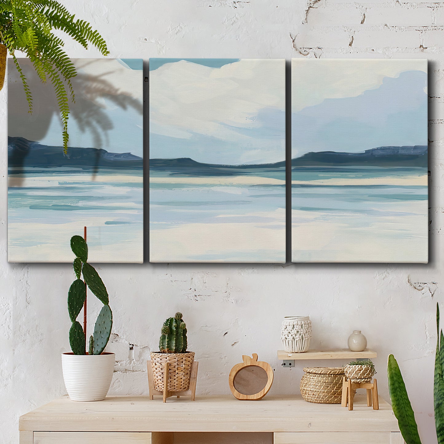 Three-panel canvas wall art featuring soft coastal shoreline landscape, displayed in a boho-chic entryway above a console table.