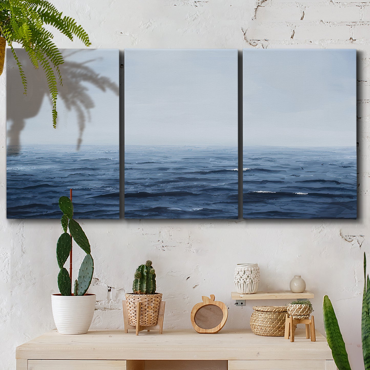 Three-panel canvas wall art featuring grayscale seascape with horizon, displayed in a boho-chic entryway above a console table.