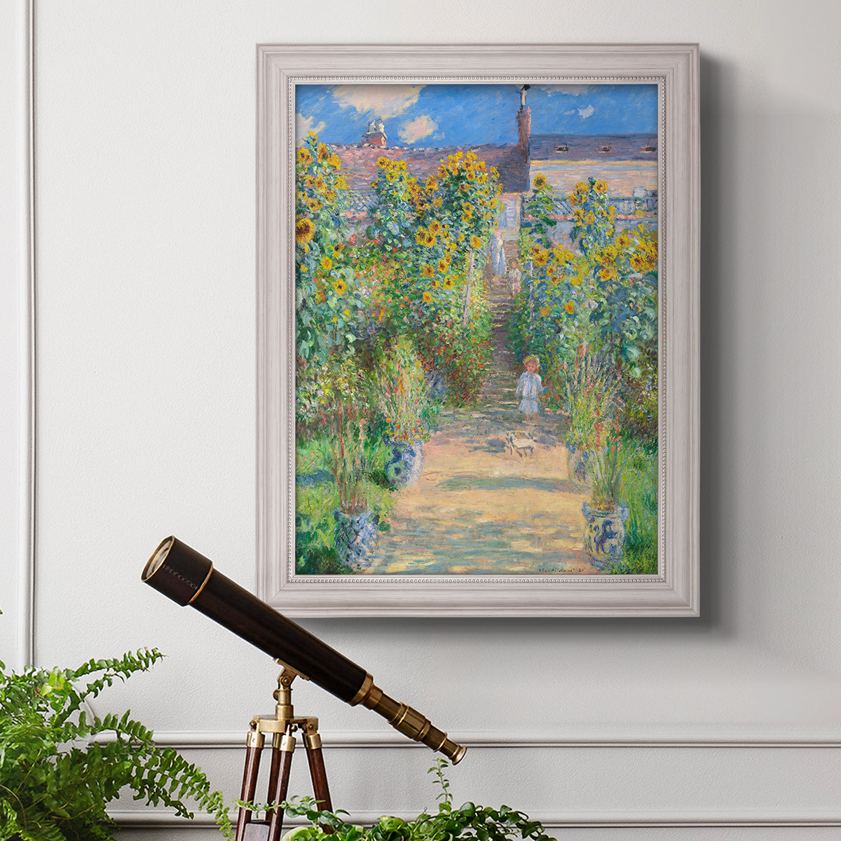 Impressionist garden landscape painting by Claude Monet in an ornate weathered white frame displayed in a light-toned interior setting.