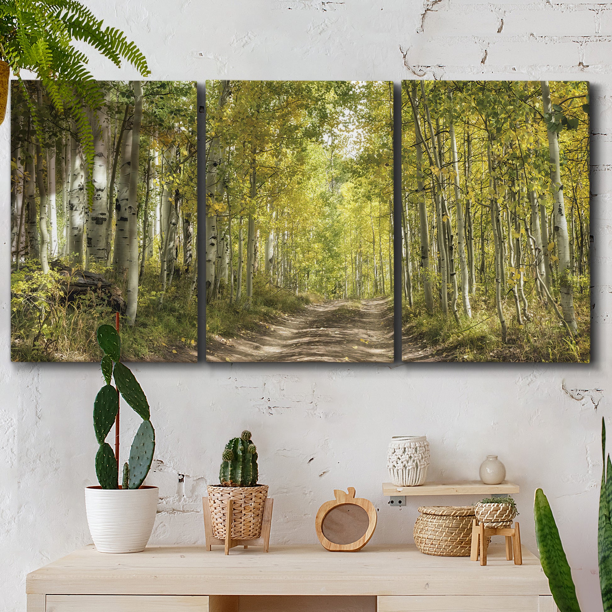 Three-panel canvas wall art featuring tree lined forest road photograph, displayed in a boho-chic entryway above a console table.