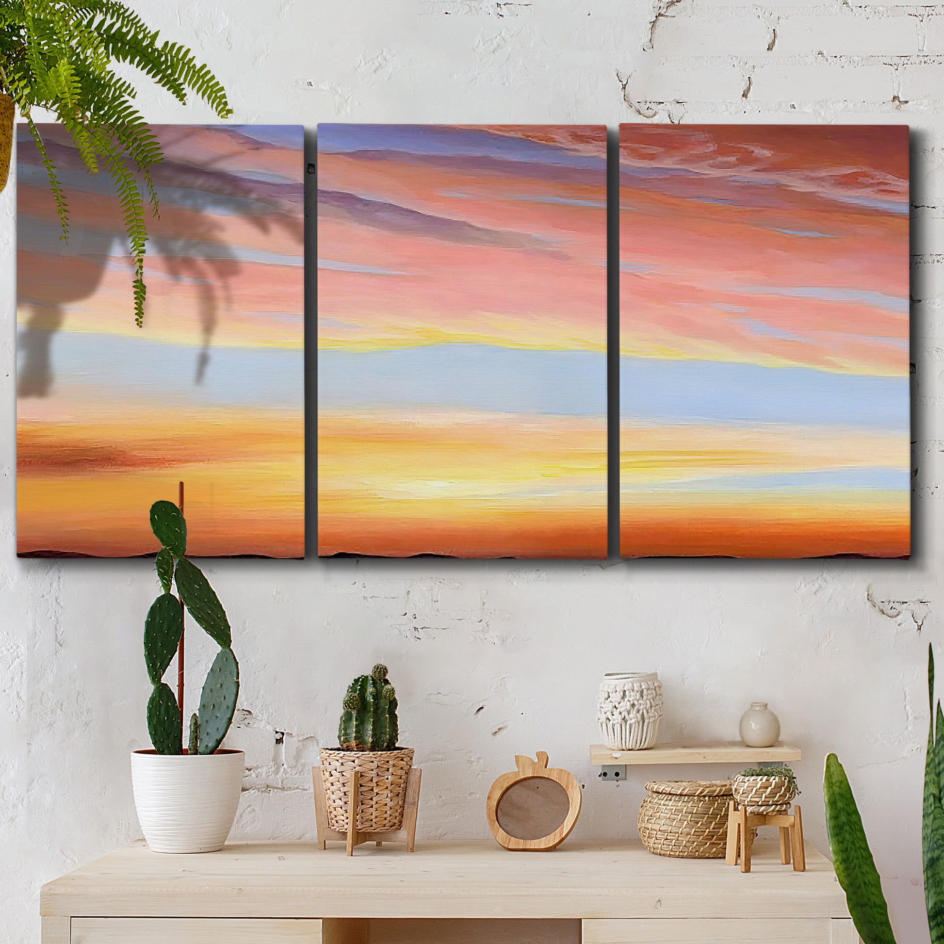 Three-panel canvas wall art featuring glowing sunset sky over landscape, displayed in a boho-chic entryway above a console table.