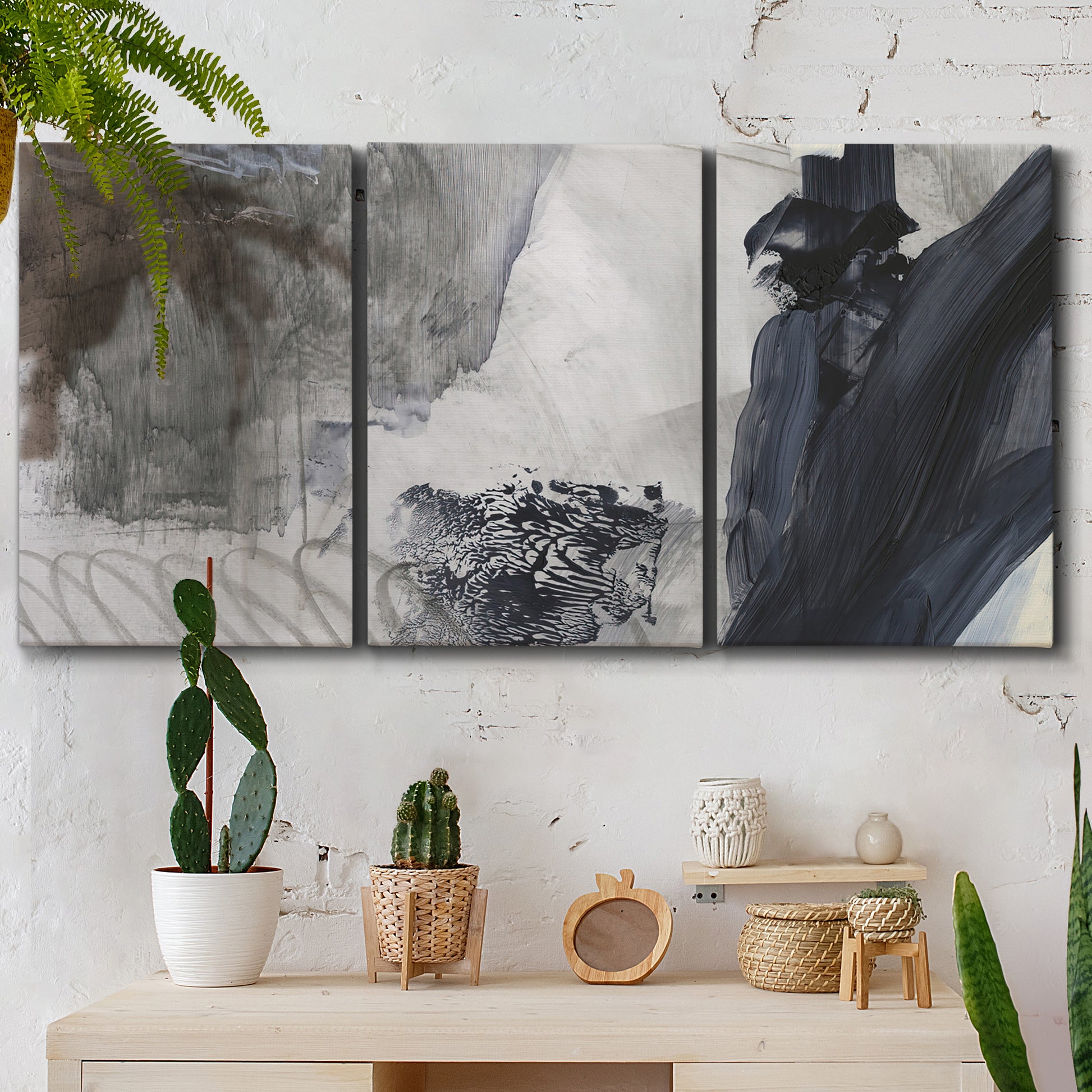Three-panel canvas wall art featuring dark abstract atmospheric landscape, displayed in a boho-chic entryway above a console table.