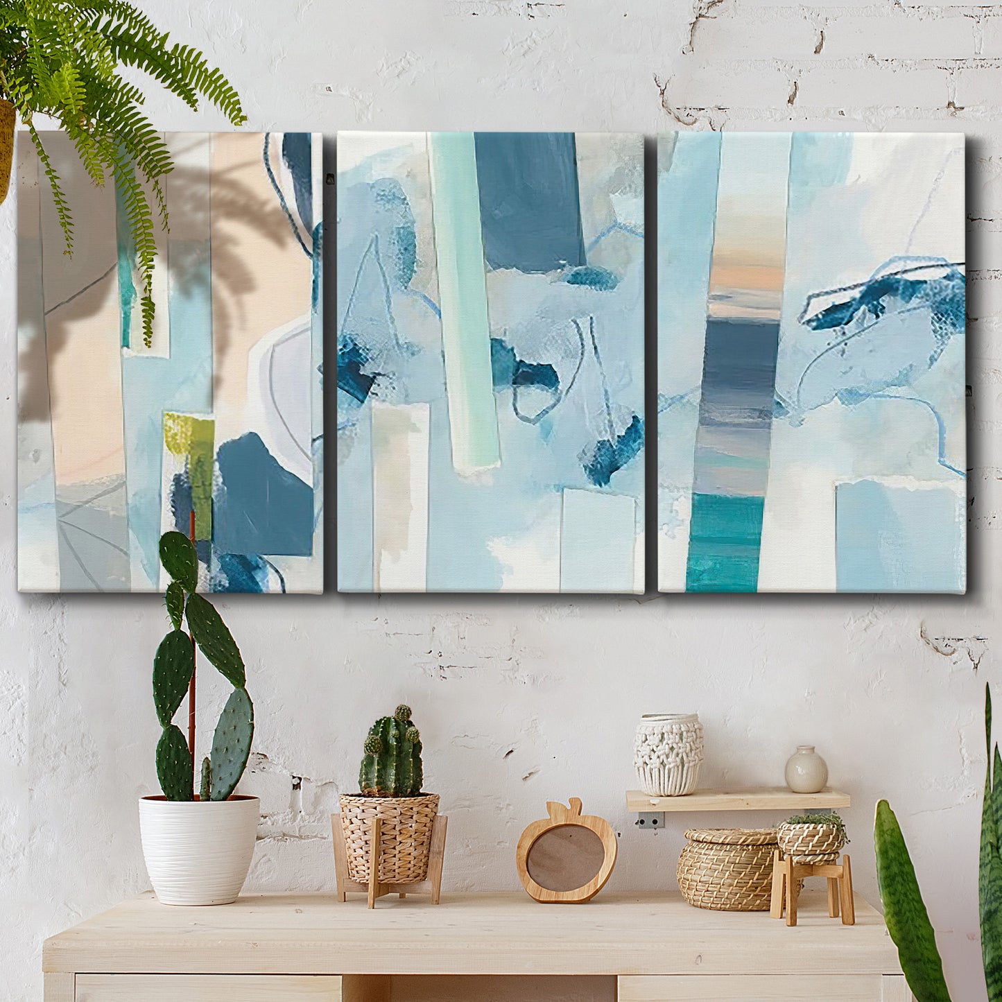 Three-panel canvas wall art featuring layered geometric abstract strata forms, displayed in a boho-chic entryway above a console table.