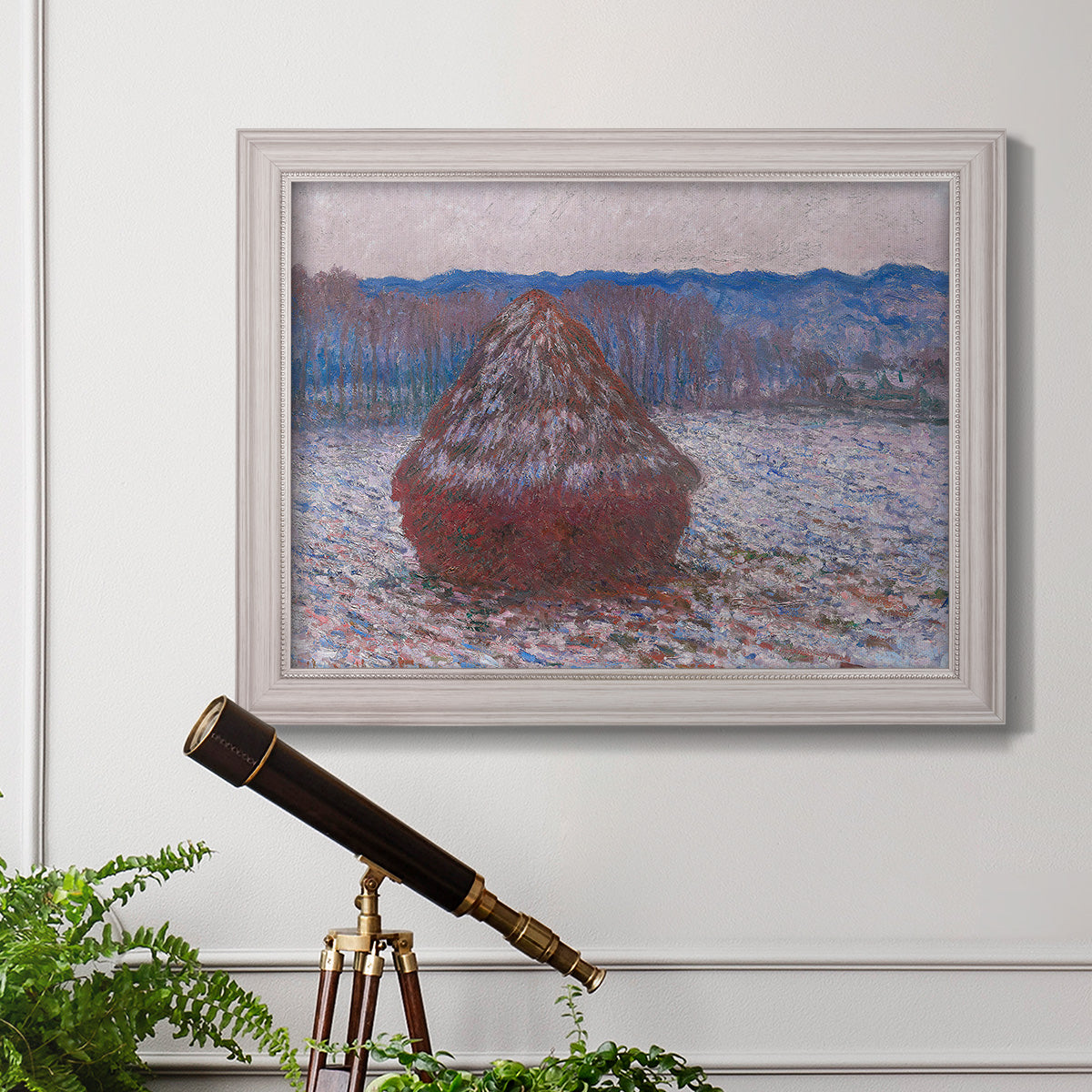 Impressionist single haystack landscape by Claude Monet in an ornate weathered white frame displayed in a light-toned interior setting.