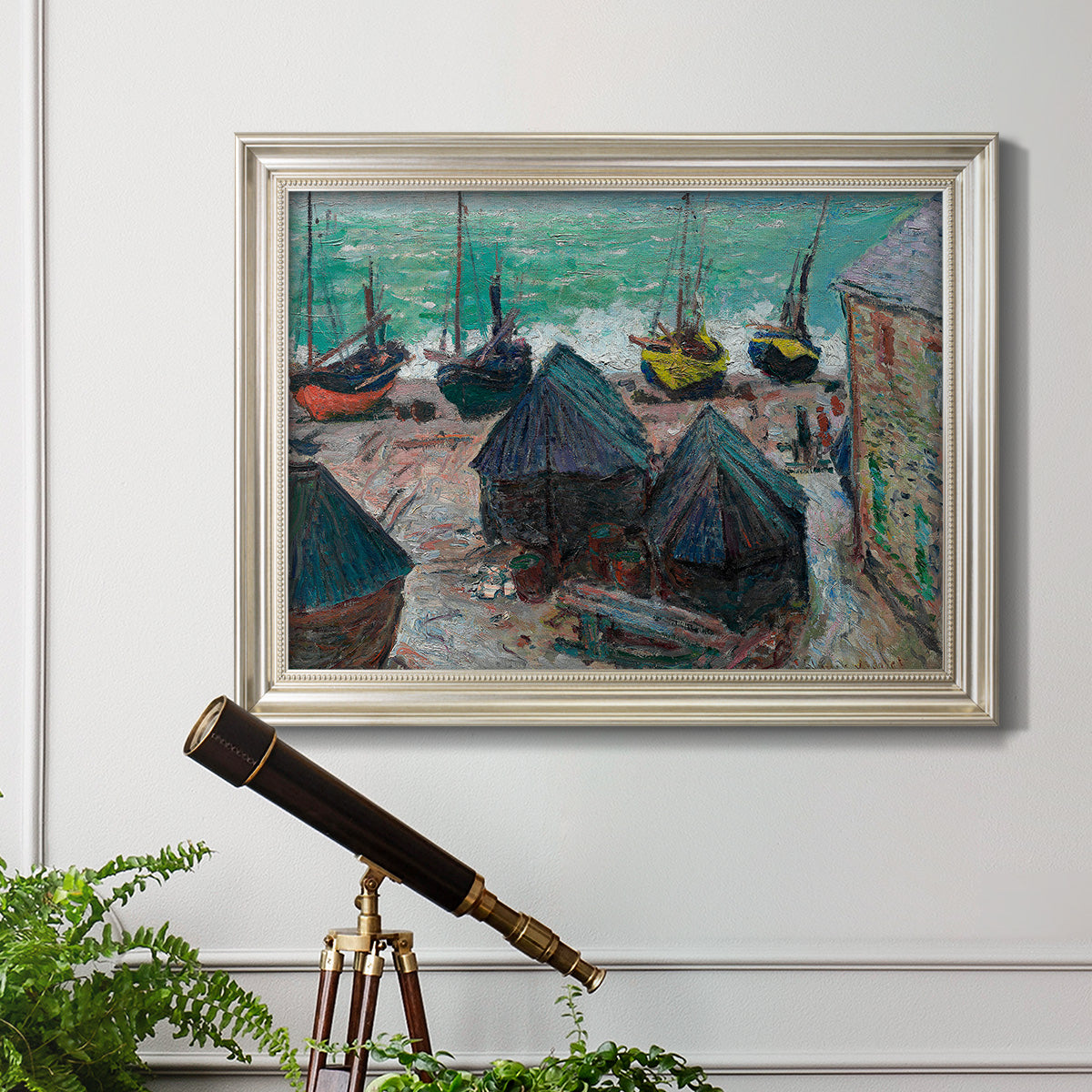 Impressionist coastal beach scene with boats by Claude Monet in an ornate champagne frame displayed in a light-toned interior setting.