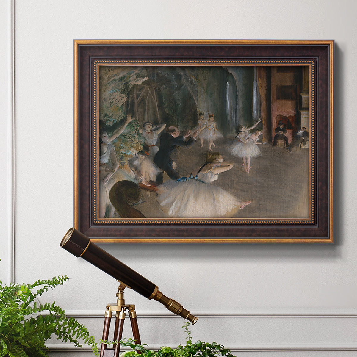 Impressionist backstage ballet scene by Edgar Degas in an ornate bronzed mahogany wood frame displayed in a light-toned interior setting.