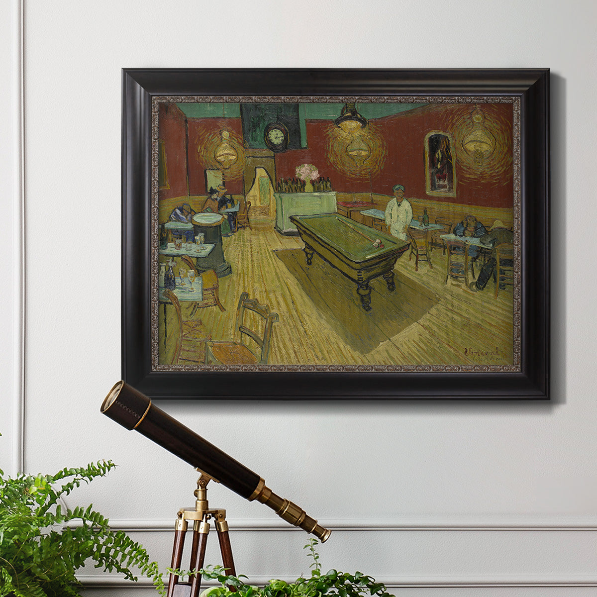 Impressionist interior of a night café by Vincent van Gogh in an ornate black frame with gilded inner detail displayed in a light-toned interior setting.